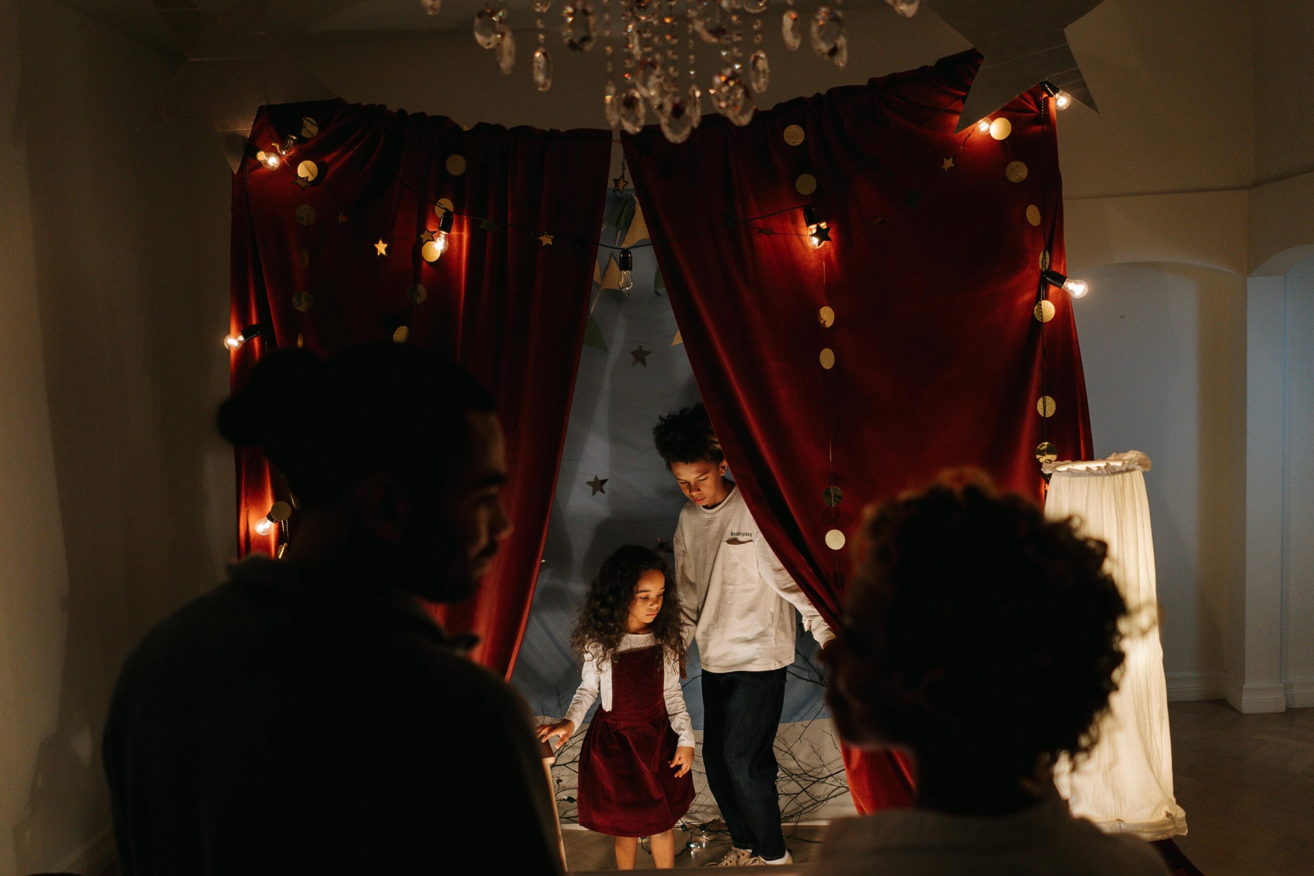 Inicio A family gathers indoors around a DIY theatre setup, creating a joyful and playful atmosphere.